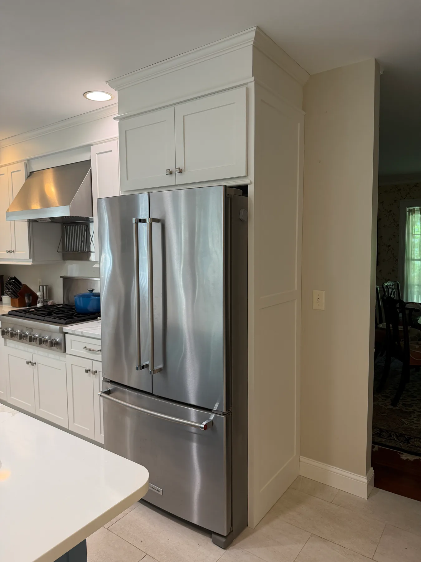 Kitchen counter run showing the stainless refrigerator, gas range, and white perimeter cabinetry